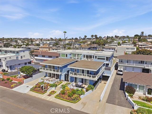 Aerial view of a blue two-story house with a manicured front yard and neighboring homes on a sunny street.
