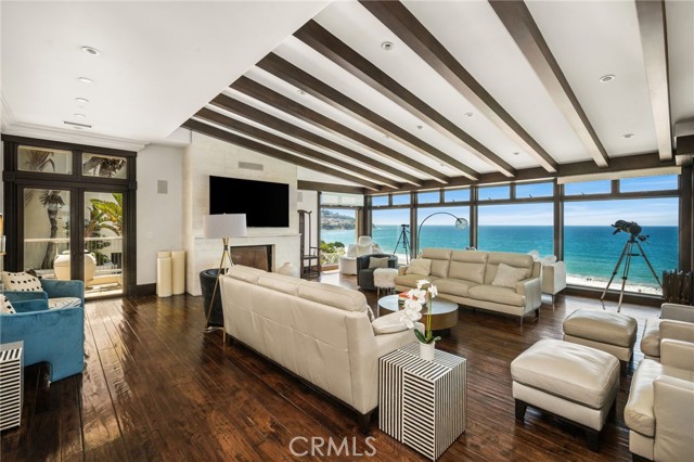Luxurious coastal living room with white sofas, dark wood floors, and a panoramic ocean view through curved glass—bright and modern.